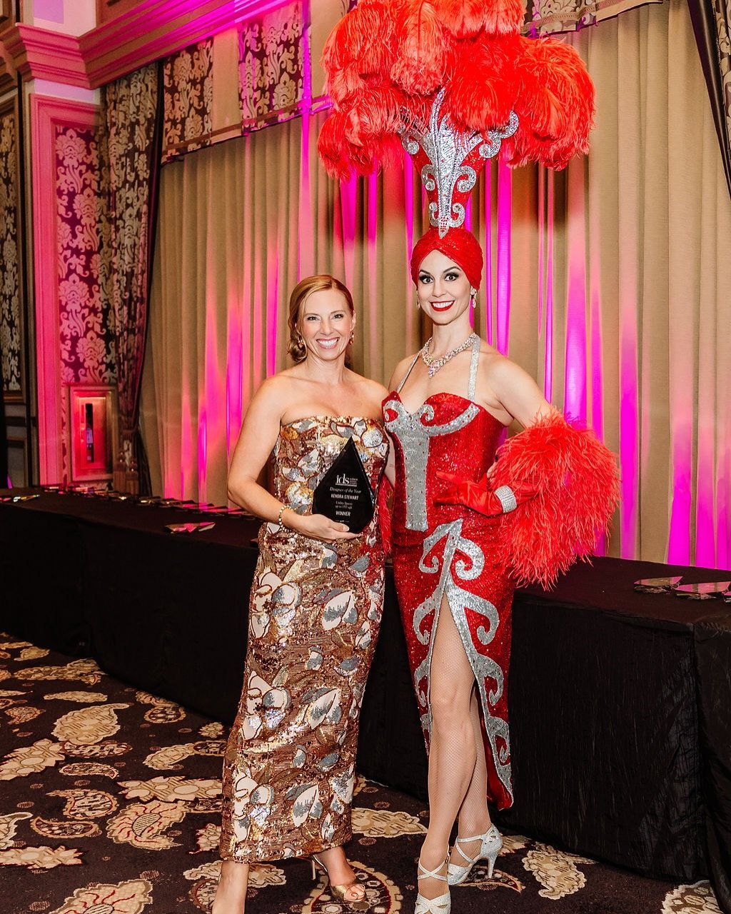 Kendra Stewart with the 2026 IDS Designer of the Year award at the gala celebration in full showgirl style.