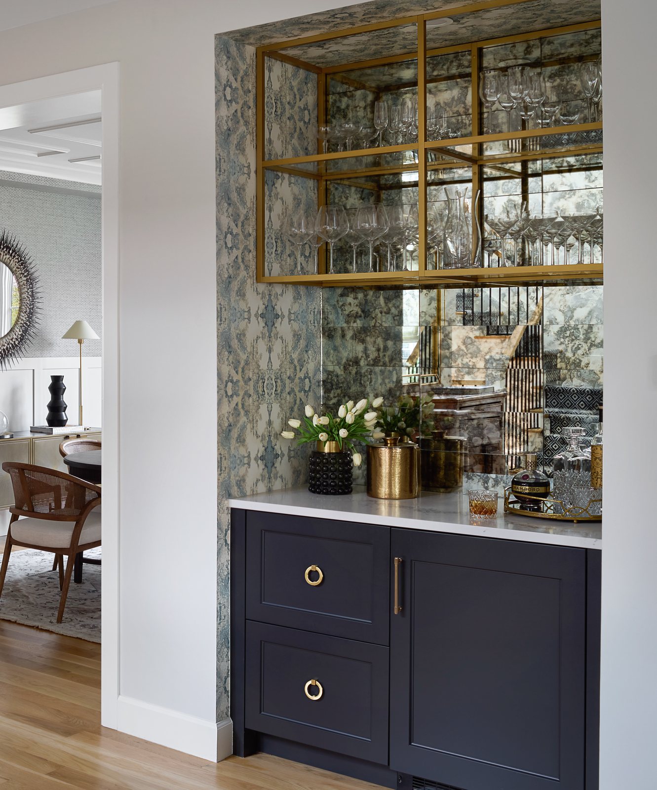 Close view of the navy bar cabinet, antiqued-mirror backsplash and brass shelves of glassware in the Bonnie Brae remodel, Denver.