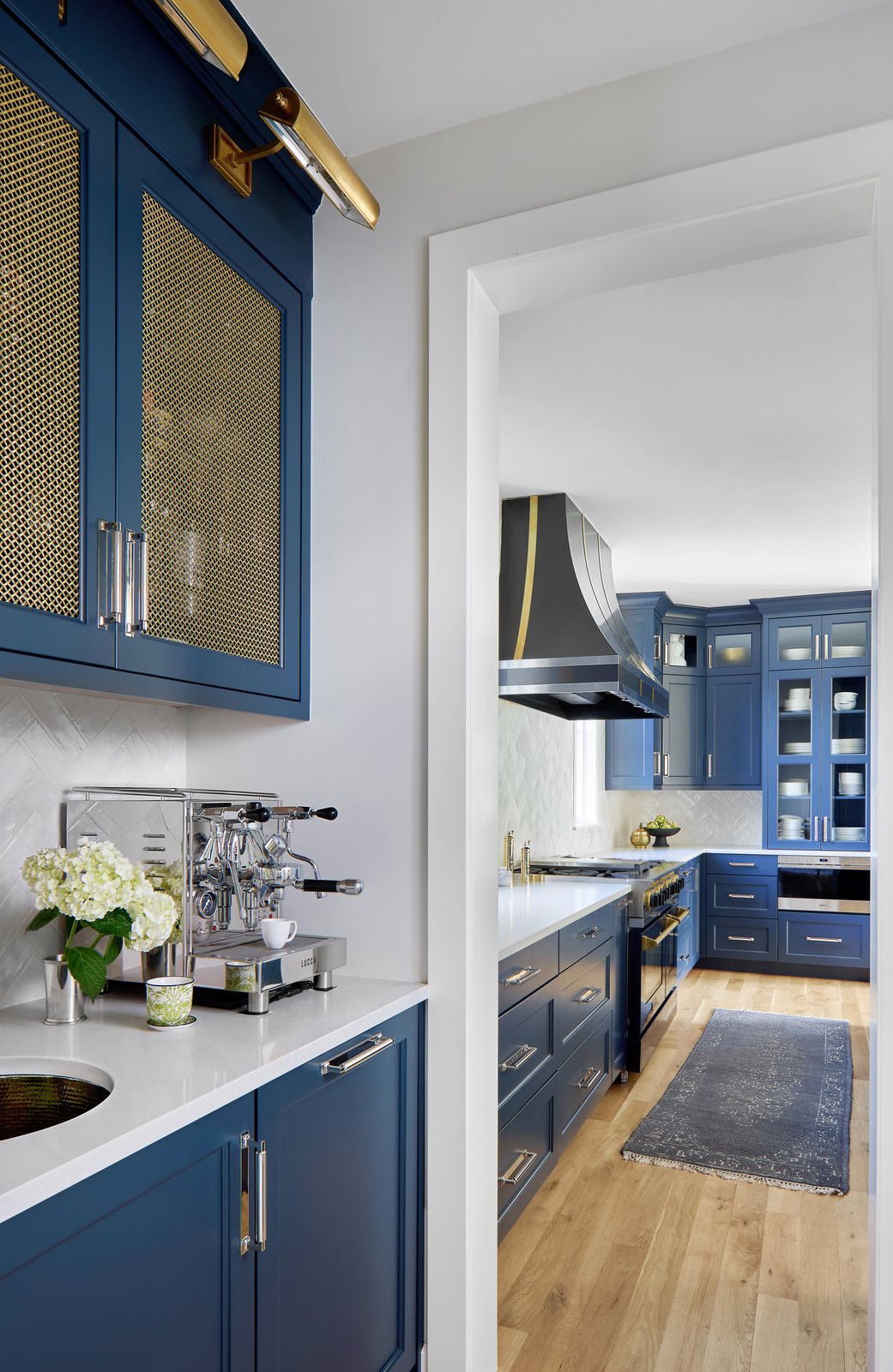 Coffee bar with brass mesh cabinet fronts and an espresso machine opening to the navy kitchen in the Bonnie Brae remodel, Denver.