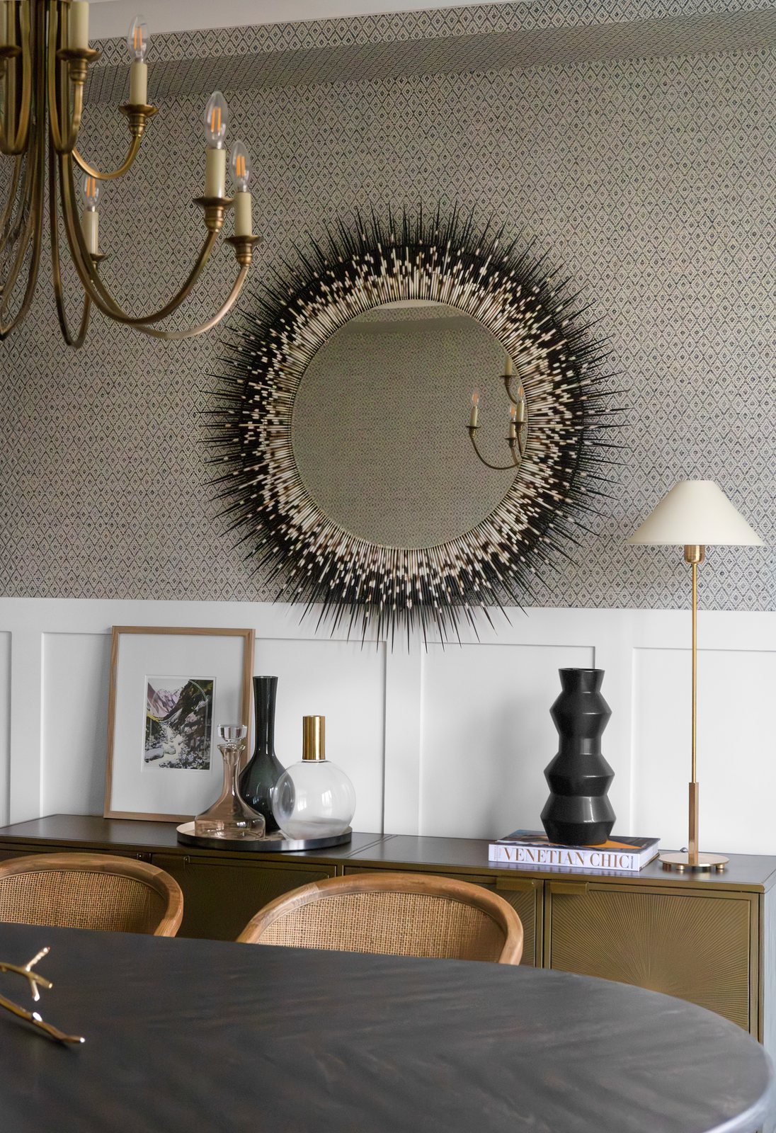 Sunburst mirror over a brass sideboard against diamond-patterned wallpaper in the Bonnie Brae dining room, Denver.