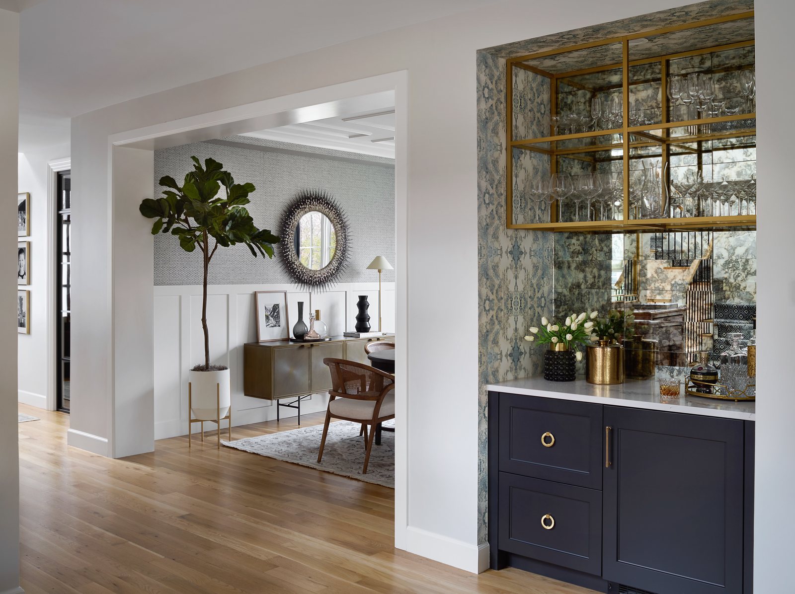 Hallway bar with antiqued-mirror backsplash and brass shelving looking through to the dining room in the Bonnie Brae remodel, Denver.