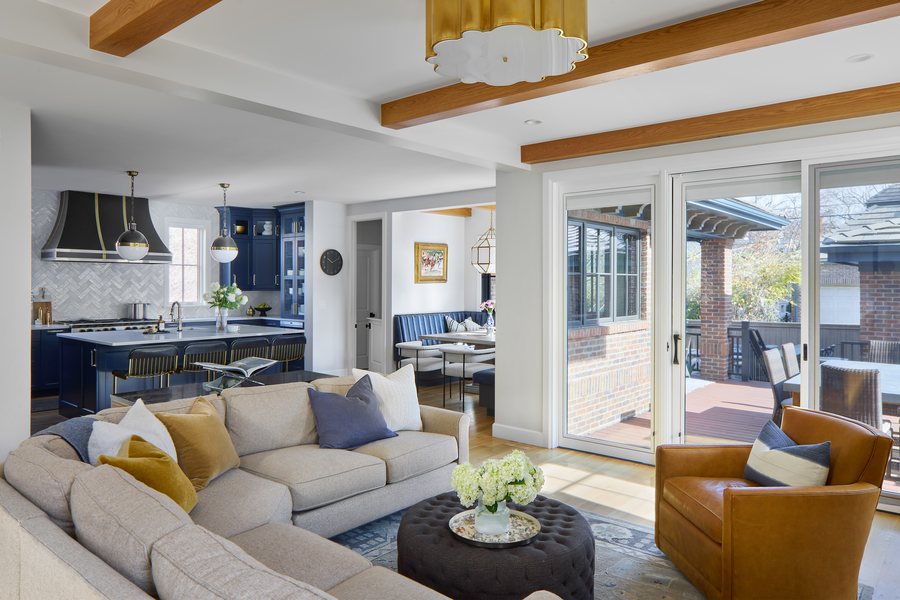 Open-plan living room with white-oak ceiling beams looking toward the navy kitchen and breakfast nook in the Bonnie Brae whole-home remodel, Denver.