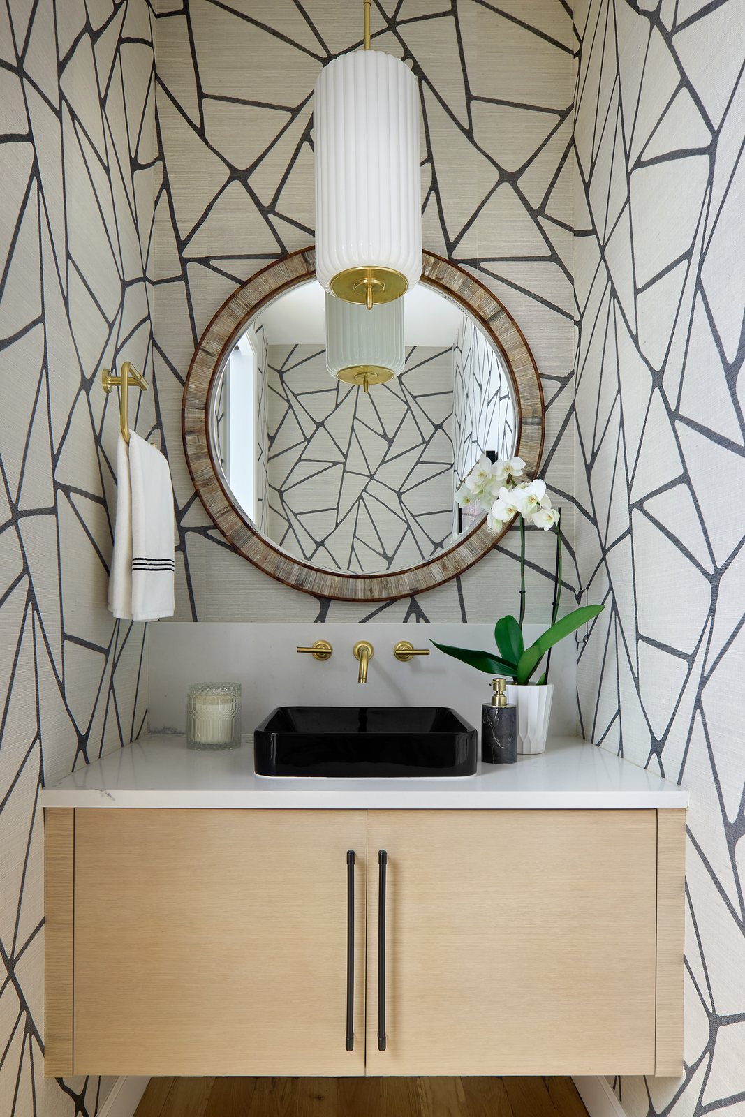 Powder room with graphic black-and-white wallpaper, a floating oak vanity and round mirror in the Bonnie Brae remodel, Denver.