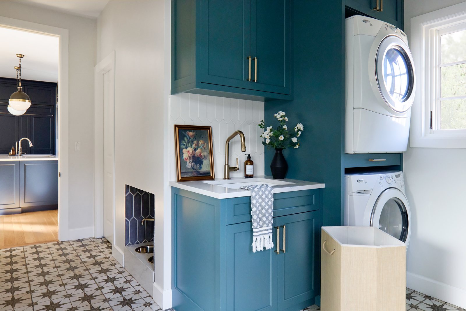 Teal cabinetry, stacked washer and dryer and patterned tile floor in the Bonnie Brae laundry room, Denver.