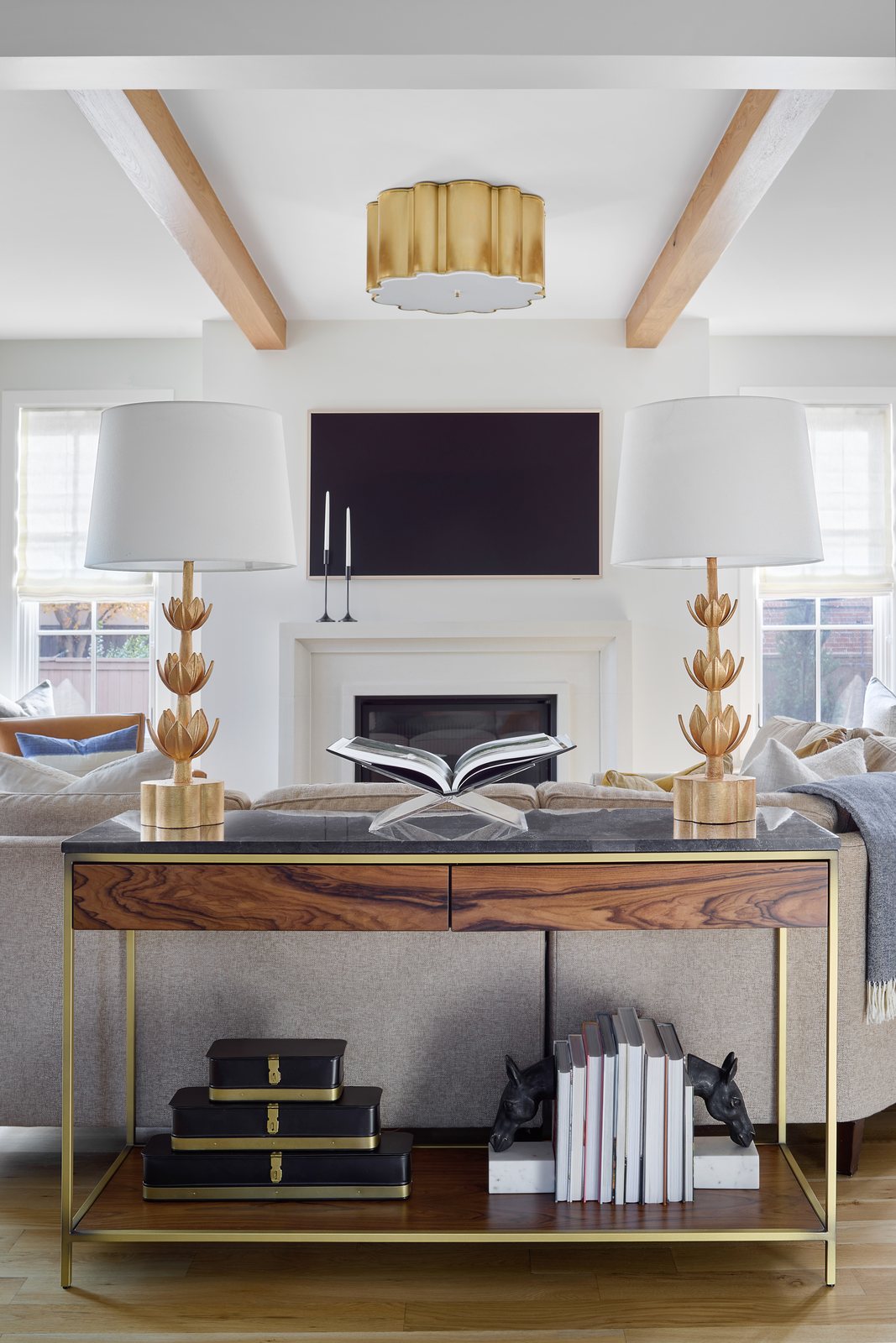 Styled wood console with twin lamps and stacked books behind the sofa in the Bonnie Brae living room, Denver.