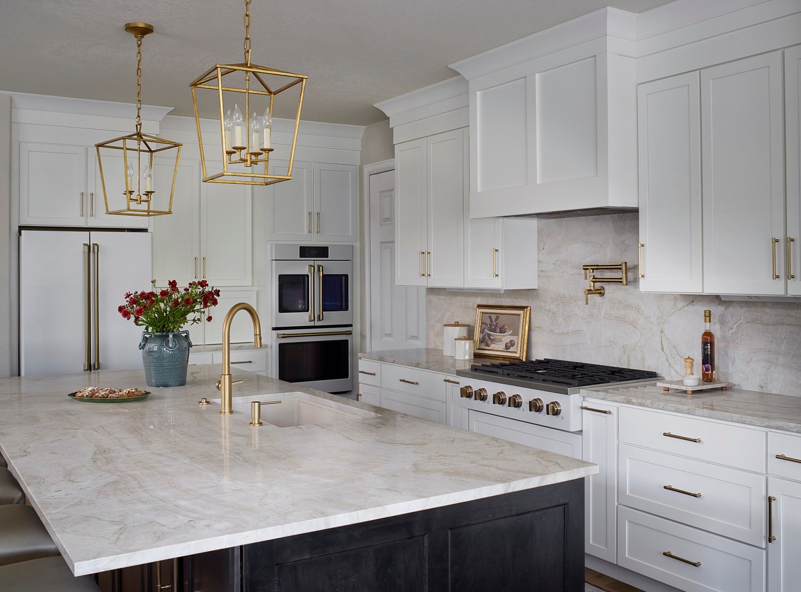 Quartzite island with a brass faucet and gold lantern pendants in the Canterberry Crossing kitchen remodel, with double ovens, a pot filler, and a full-height stone backsplash