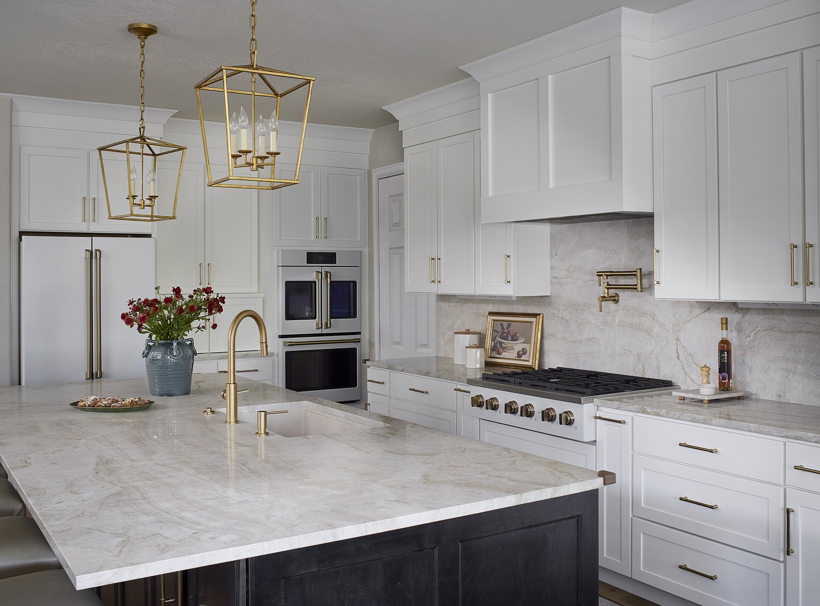 Quartzite island with a brass faucet and gold lantern pendants in the Canterberry Crossing kitchen remodel, with double ovens, a pot filler, and a full-height stone backsplash