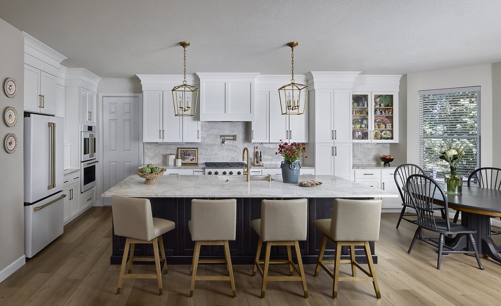 Remodeled kitchen in Canterberry Crossing, Parker, with white cabinetry, a black island with leather counter stools, brass lantern pendants, and a paneled refrigerator