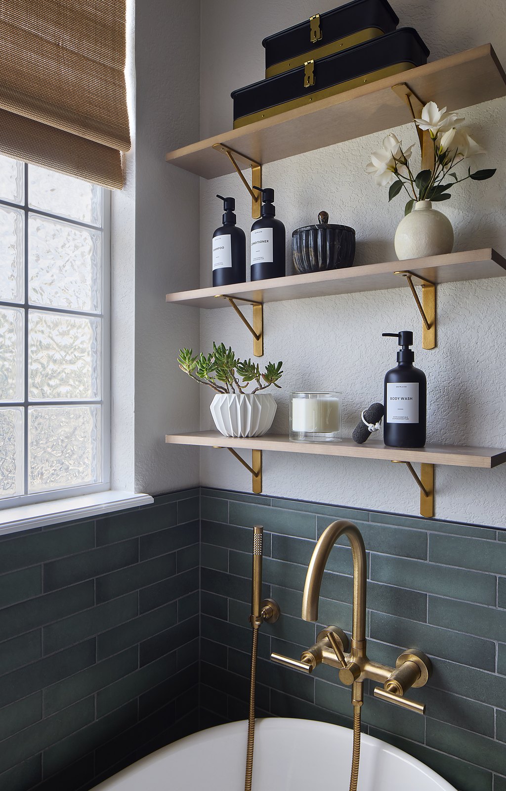 Brass tub filler against green tile with styled wood open shelving in the Canterberry Crossing primary bathroom remodel