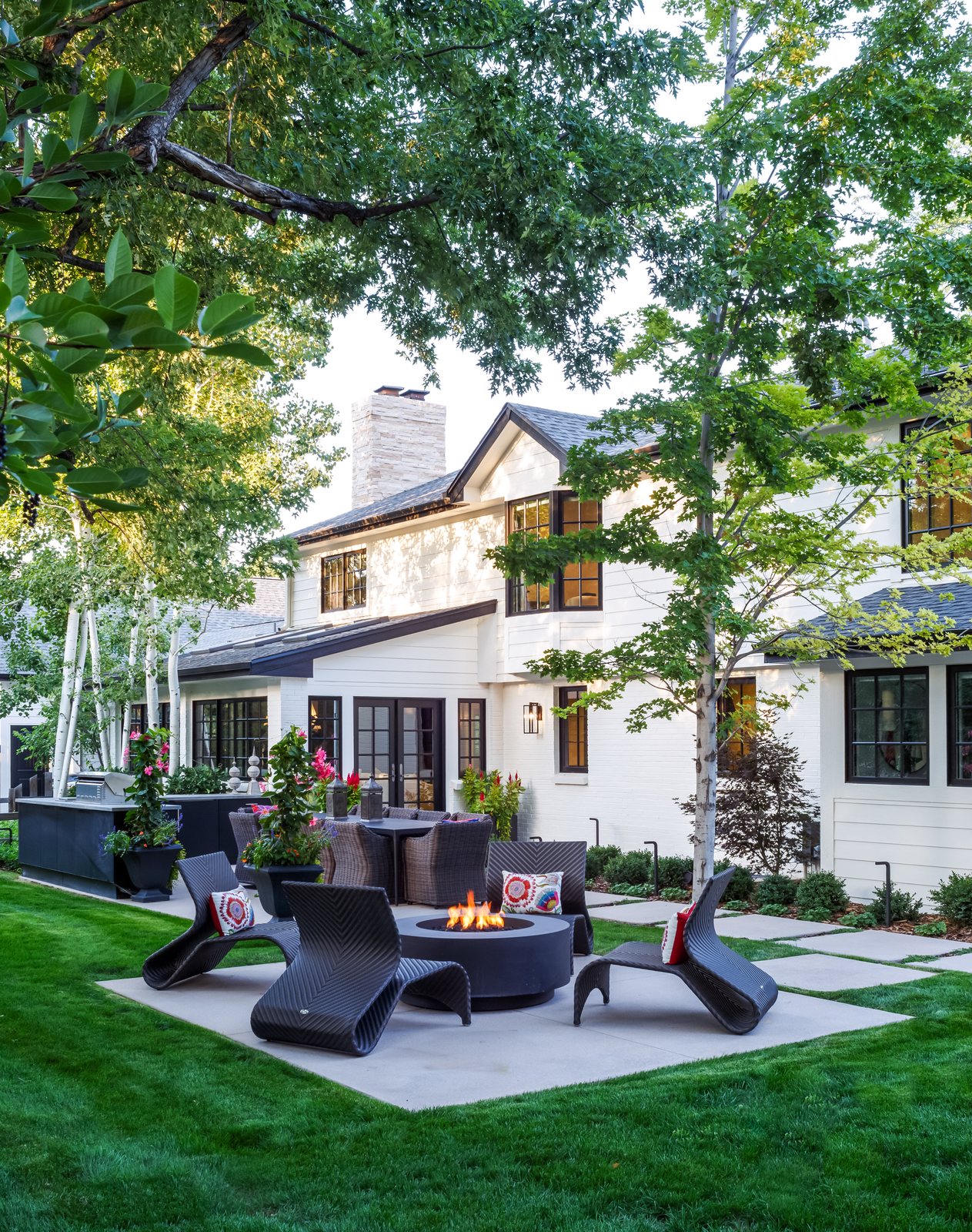 Woven lounge chairs around a lit fire pit on the back patio of the Greenwood Village whole-home remodel.