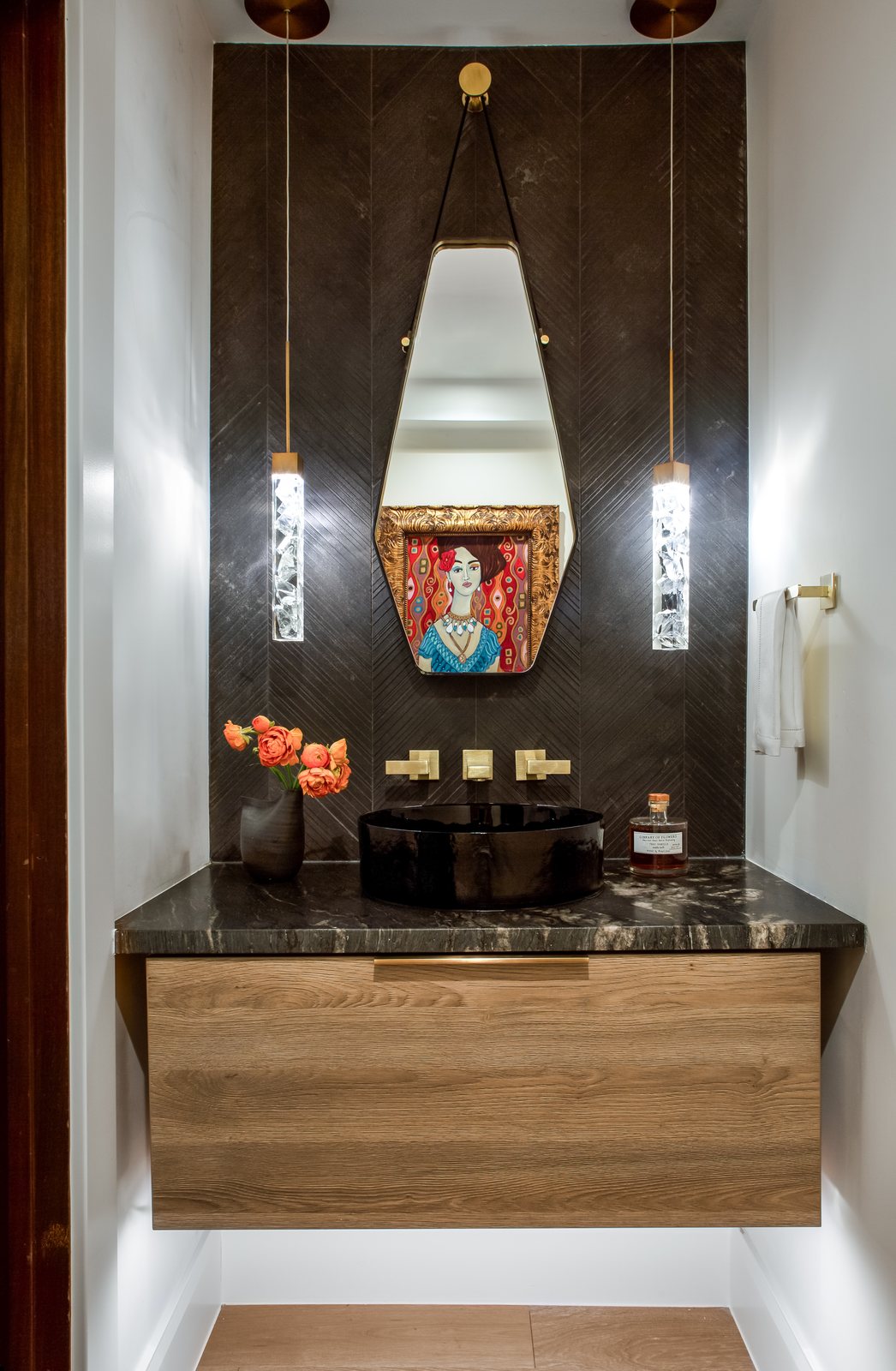 Floating wood vanity with dark stone counter, hanging pendants and framed art in a bathroom of the Greenwood Village whole-home remodel.