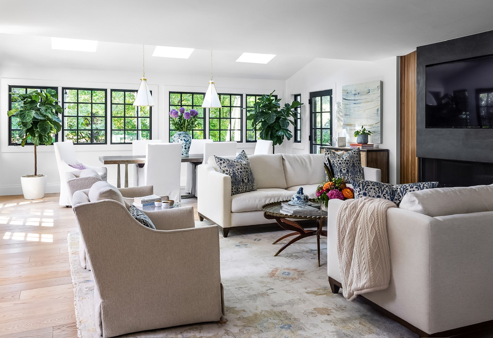 Light-filled great room with white sofas, blue ikat pillows and a dining area beyond in the Greenwood Village whole-home remodel.