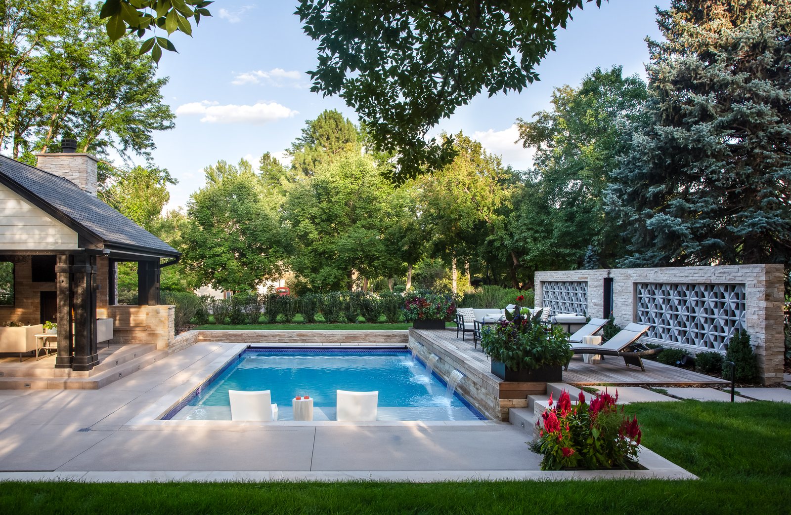 Rectangular pool with in-water loungers, waterfall spouts and a breeze-block privacy wall at the Greenwood Village whole-home remodel.