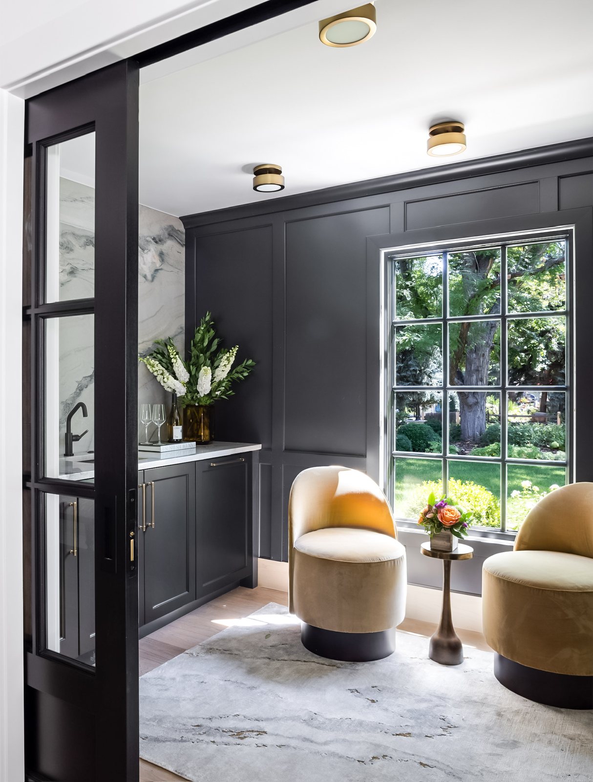 Camel swivel chairs in a sitting room seen through black-framed glass doors in the Greenwood Village whole-home remodel.