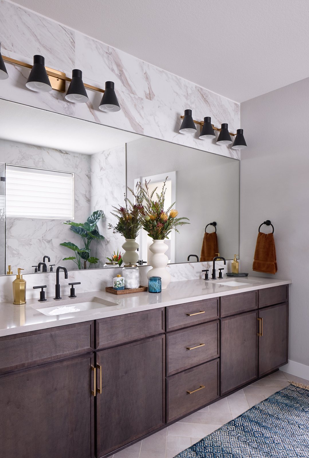 Double vanity with dark-stained cabinetry, brass pulls and black cone sconces in the same Canyons bathroom, Castle Pines.