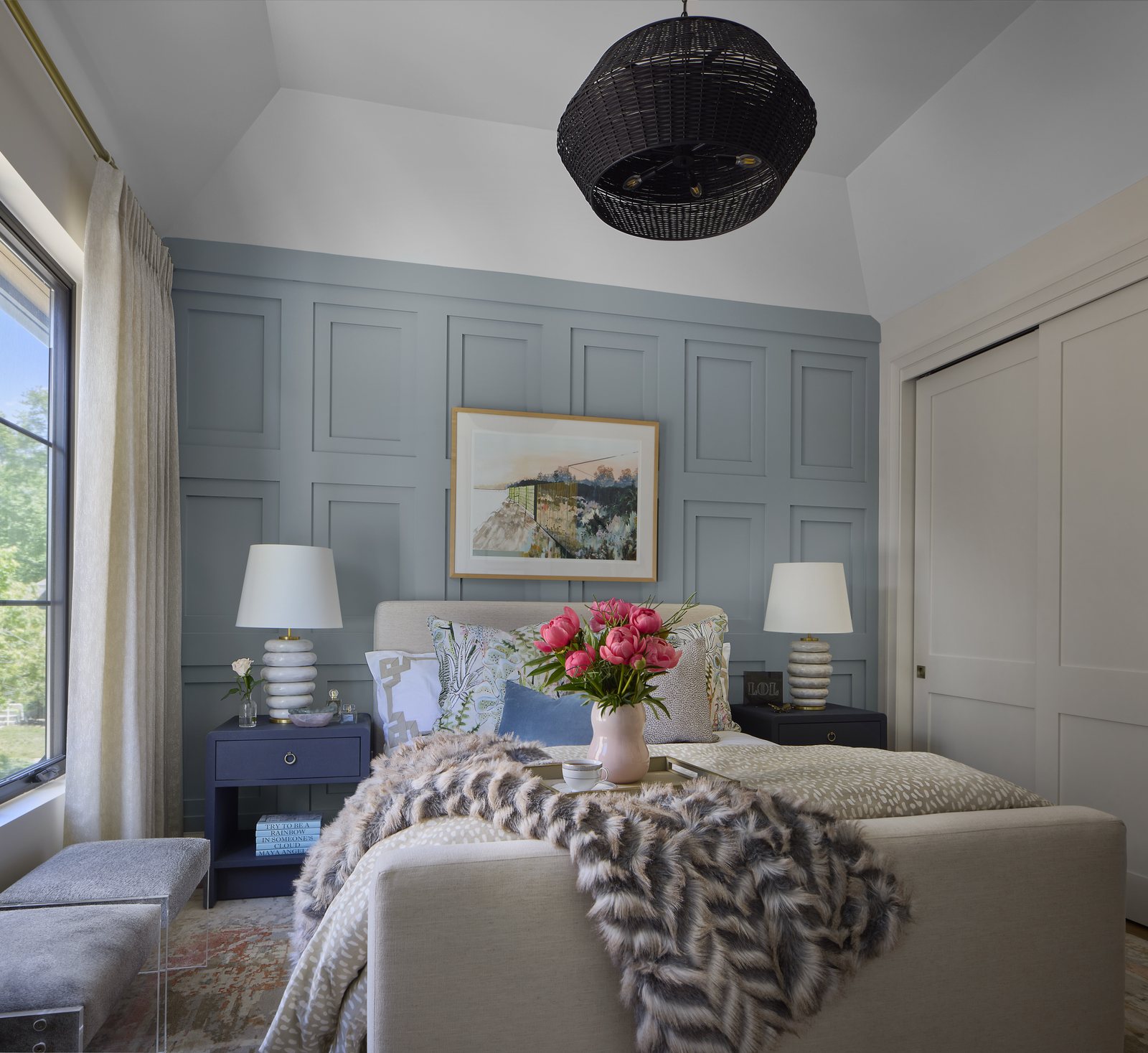 Straight-on view of the showhouse bedroom in Washington Park, Denver, with coral peonies on a tray, a faux-fur throw, and a black rattan pendant over the bed.