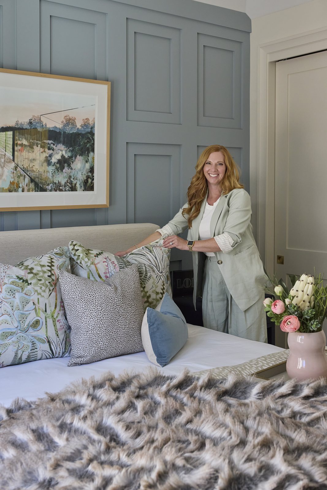 Kendra Stewart arranges patterned pillows on the bed in the Washington Park showhouse bedroom in Denver.