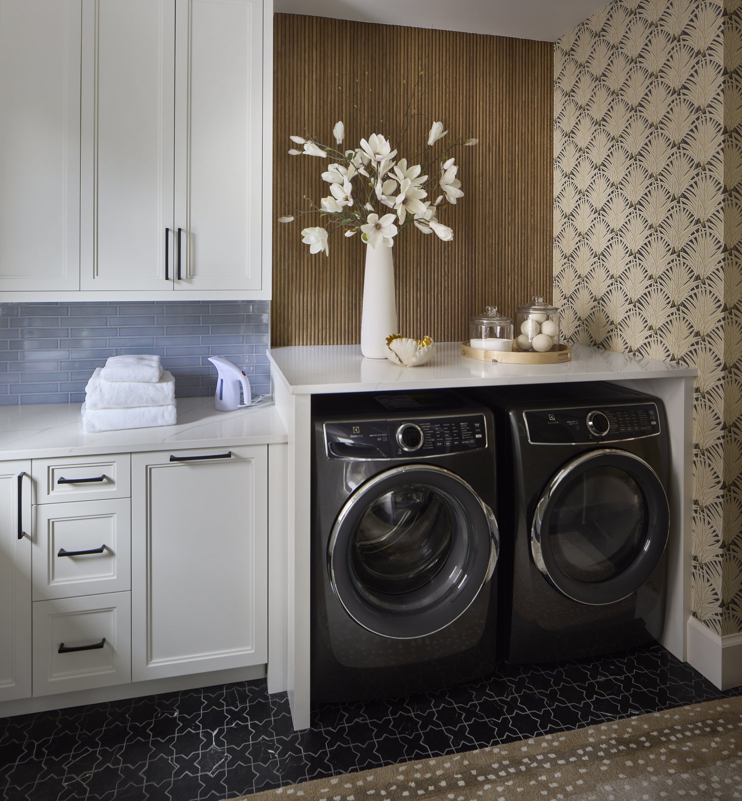 Magnolia branches in a white vase above the black washer and dryer in the Washington Park showhouse laundry room in Denver.