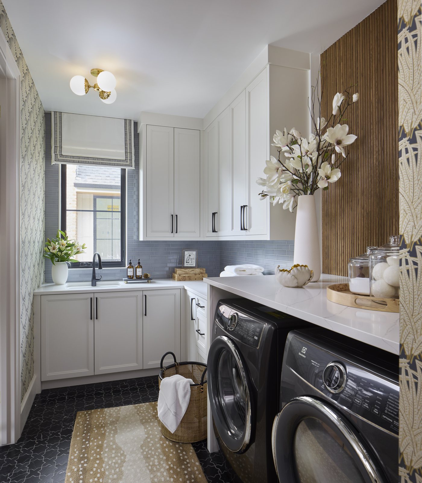 The Washington Park showhouse laundry room in Denver styled with a tall vase of magnolia branches on the quartz counter over the washer and dryer.