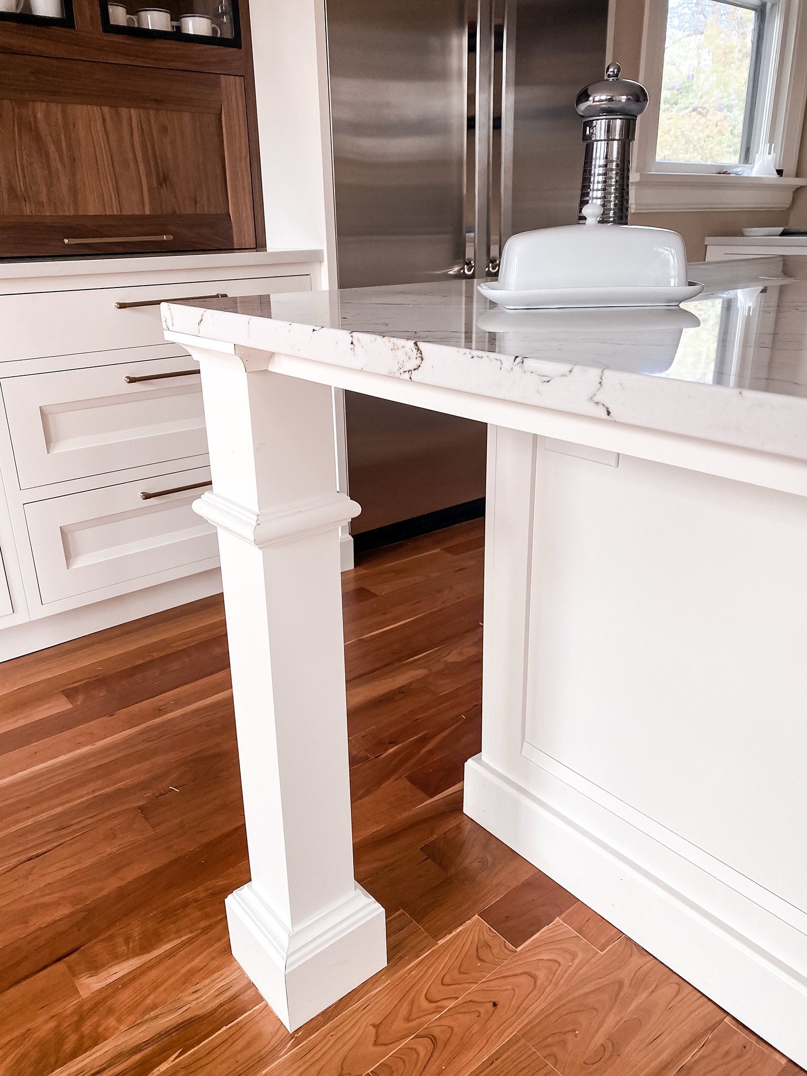 Island leg detail with walnut accents and stainless fridge beyond, historic Colorado Springs kitchen remodel