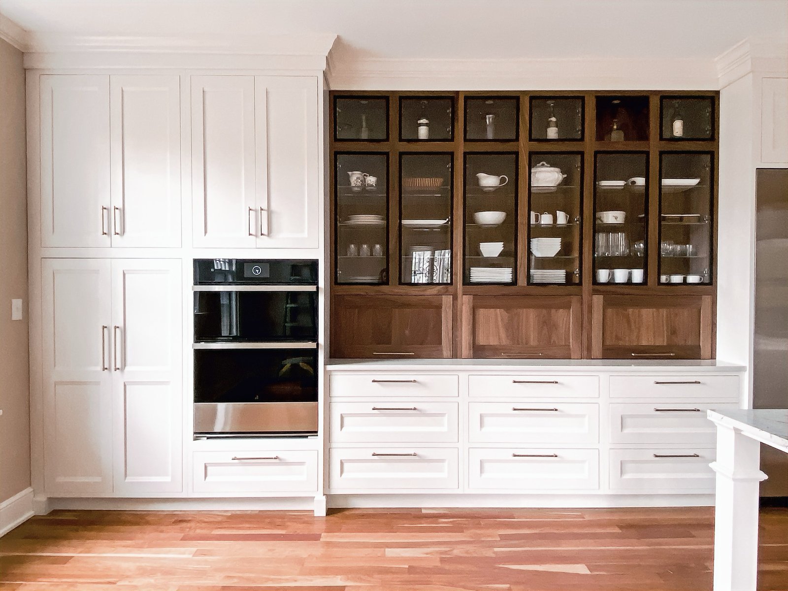 Two-tone cabinet wall with metal-framed glass doors and hidden appliance storage, historic Colorado Springs kitchen remodel