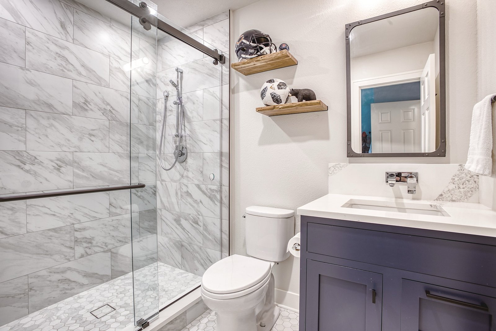 Guest bath with sliding glass shower and navy vanity, Fulton Street whole house renovation in Greenwood Village