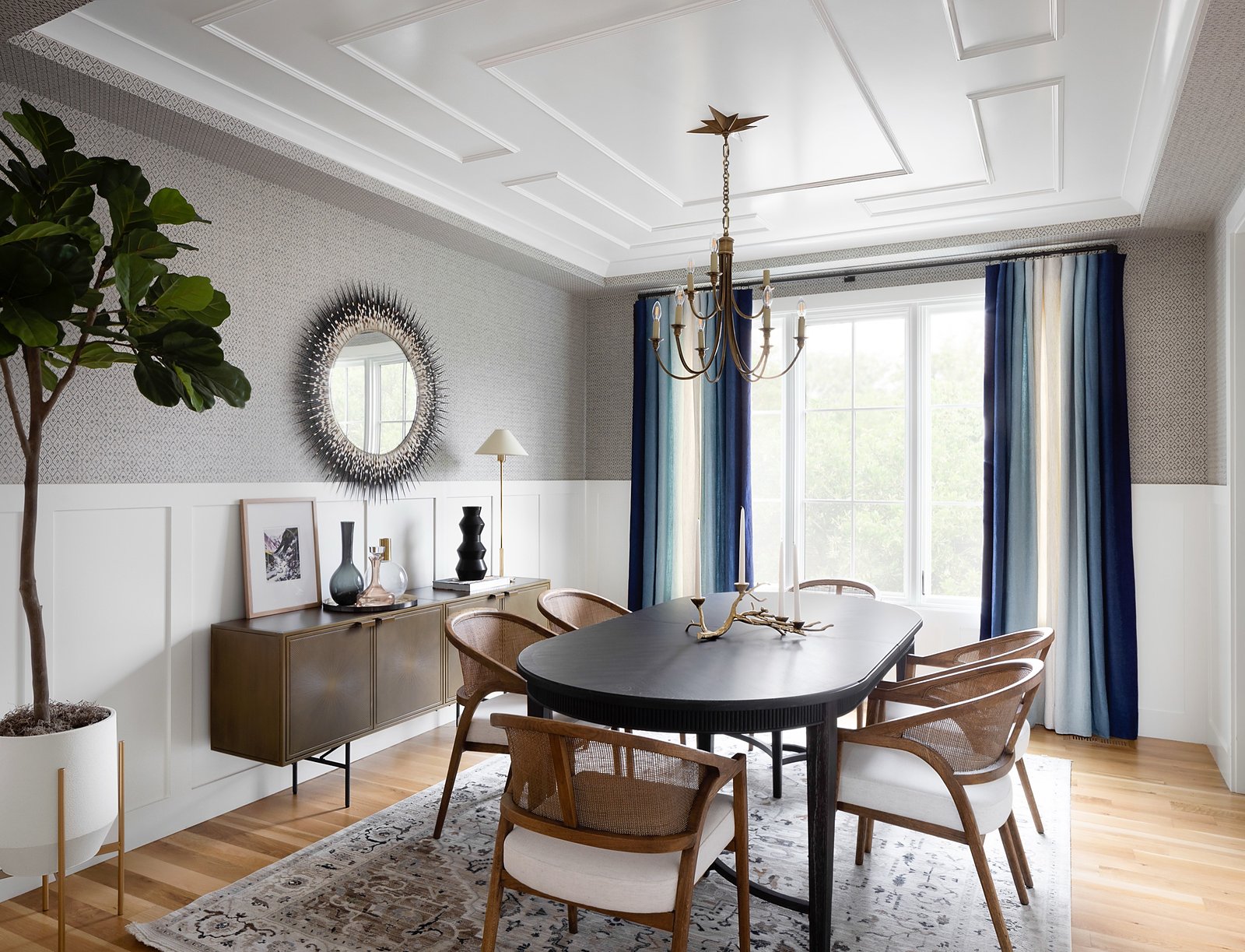 Channel-tufted navy banquette dining nook beneath white oak beams and a brass lantern pendant, whole home renovation by E+E