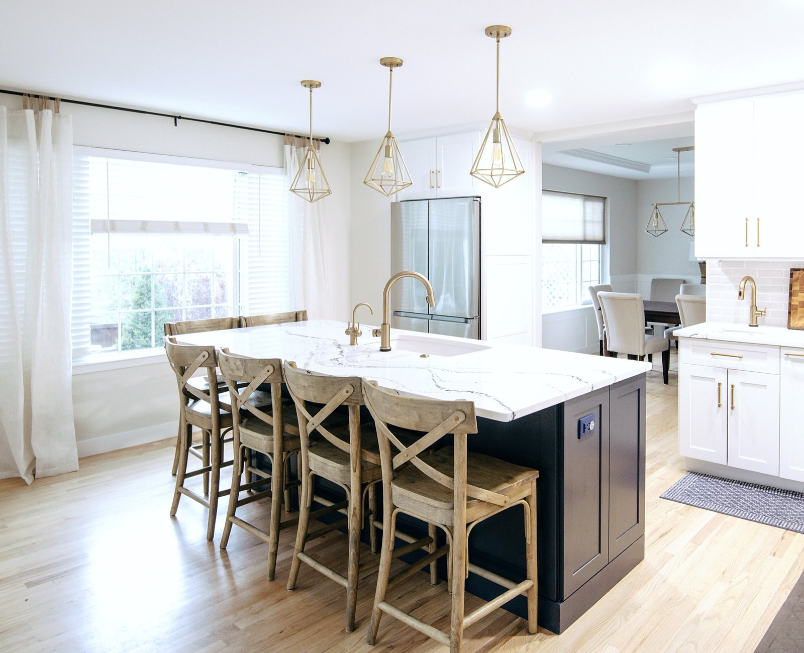 White kitchen with navy island, marble-look quartz, and woven counter stools, Stonegate main floor renovation in Parker, Colorado