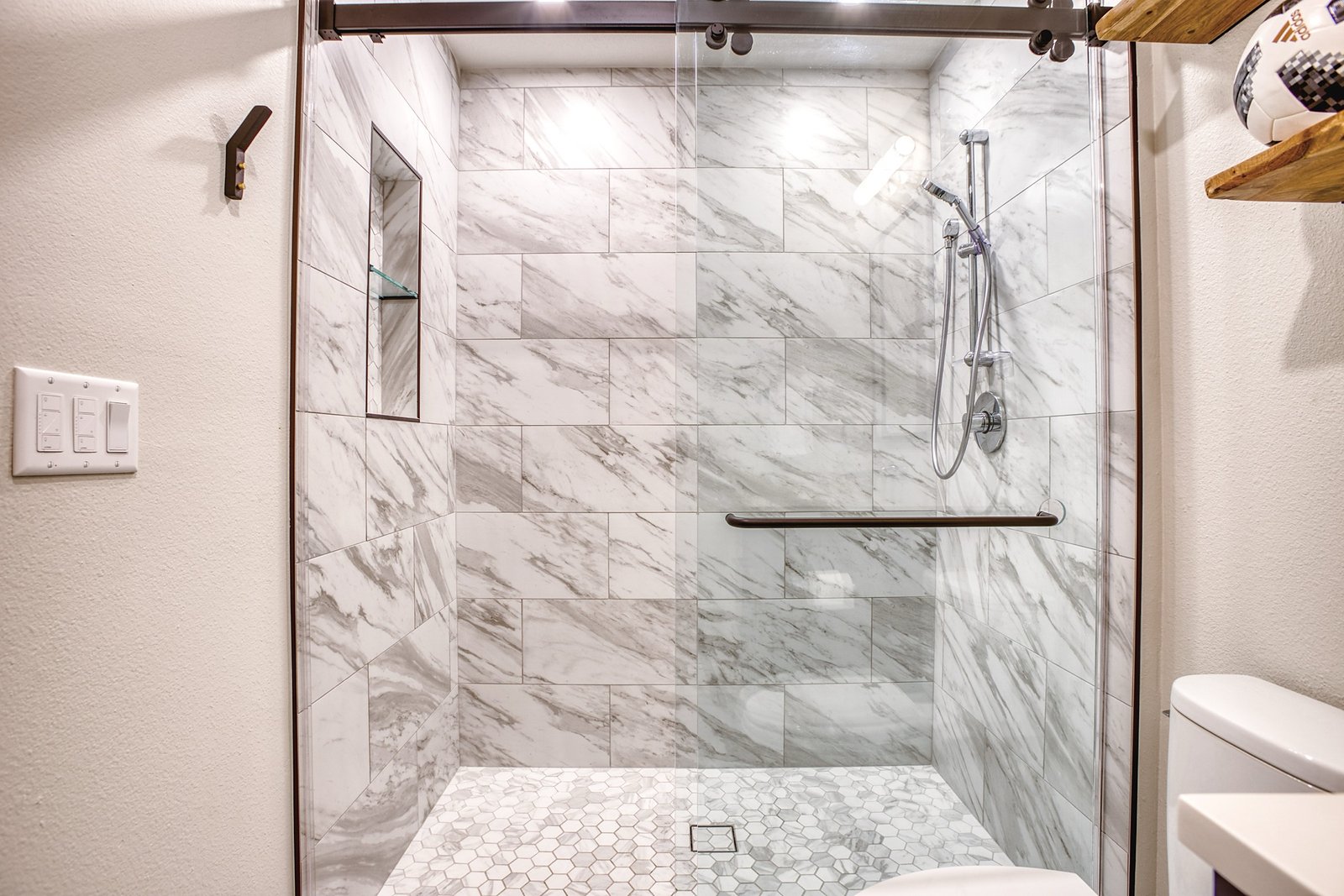 Marble-look shower with hex-tile floor and floating shelves, Fulton Street whole house renovation in Greenwood Village