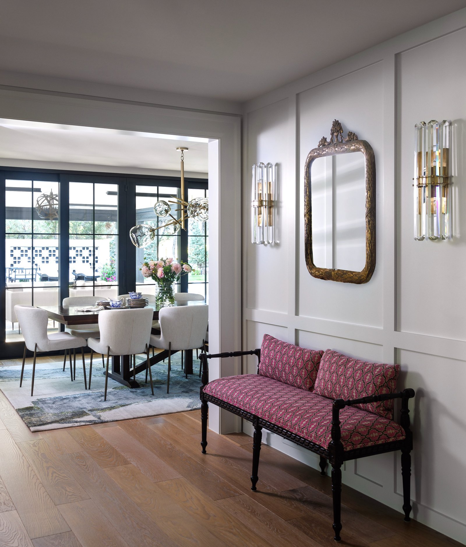 White paneled hallway with antique bench and view to the dining room in the Greenwood Village renovation by E+E
