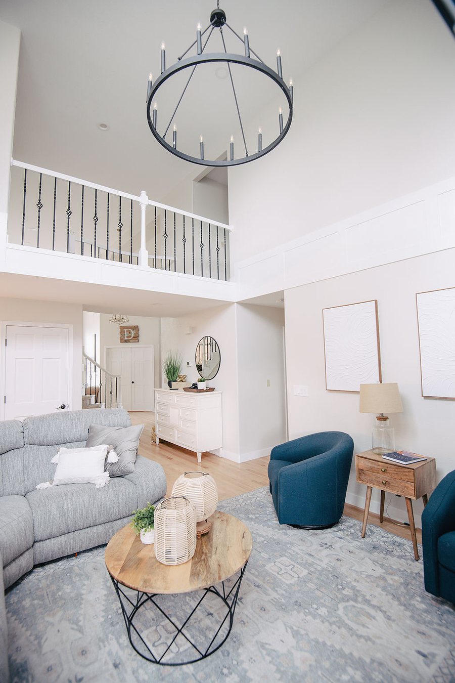 Living room with gray sectional, teal accent chairs, and balcony overlook, Stonegate main floor renovation in Parker, Colorado
