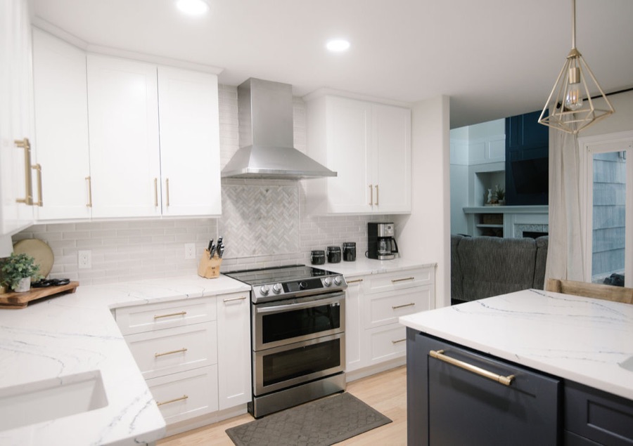 Kitchen with white cabinetry, gold hardware, and stainless range hood, Stonegate main floor renovation in Parker, Colorado