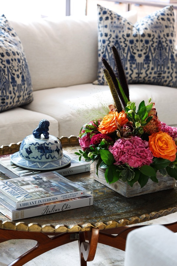 Styling detail with fresh florals, blue-and-white porcelain, and layered books on a curated coffee table