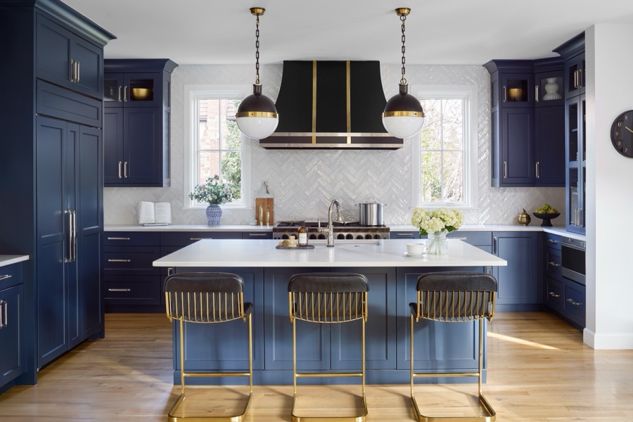 Navy island kitchen with brass hardware, black-and-gold hood, and white herringbone backsplash designed by E+E in Denver