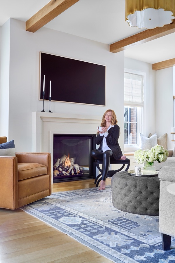 Refreshed living room with camel leather chair, layered rug, and styled fireplace by E+E Design Consulting